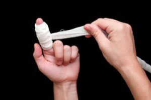 Бинтует ушибленный палец