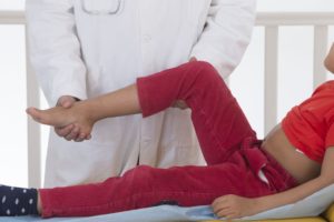 Ребенку разминает ногу Ребенку массажирует ногу