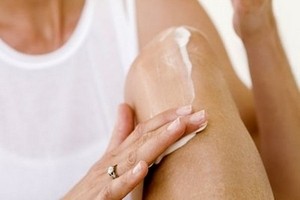 Женщина намазывает коленку Женщина мажет коленку